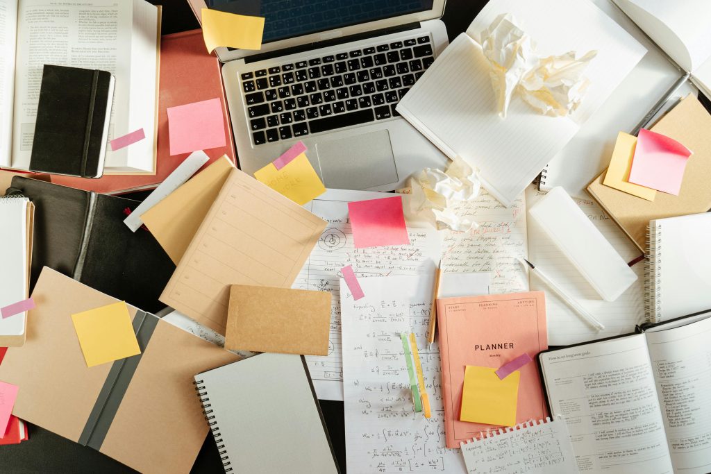 Can AI Really Replace Your Bookkeeper? Here's the Truth Small Business Owners Need Flatlay of a messy study desk with laptop, notebooks, and sticky notes, showcasing the creative process.